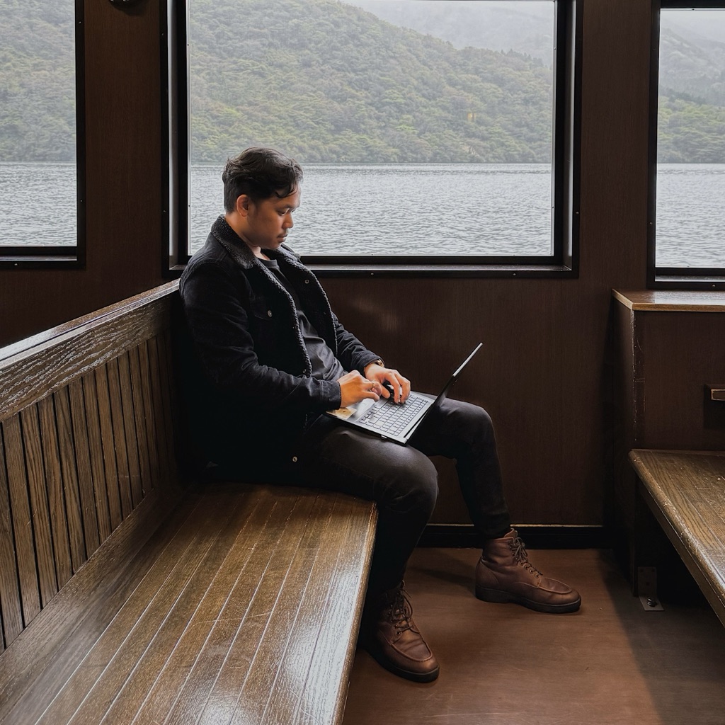 Fabio Jonathan working on a laptop aboard a ferry in Hakone, Japan